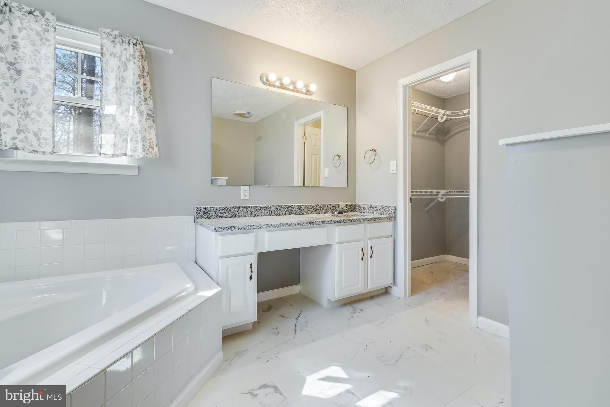 648 Santa Fe Trail Lusby, MD 20657 - Photo 26 of 58 a spacious bathroom with a granite countertop sink mirror and bathtub