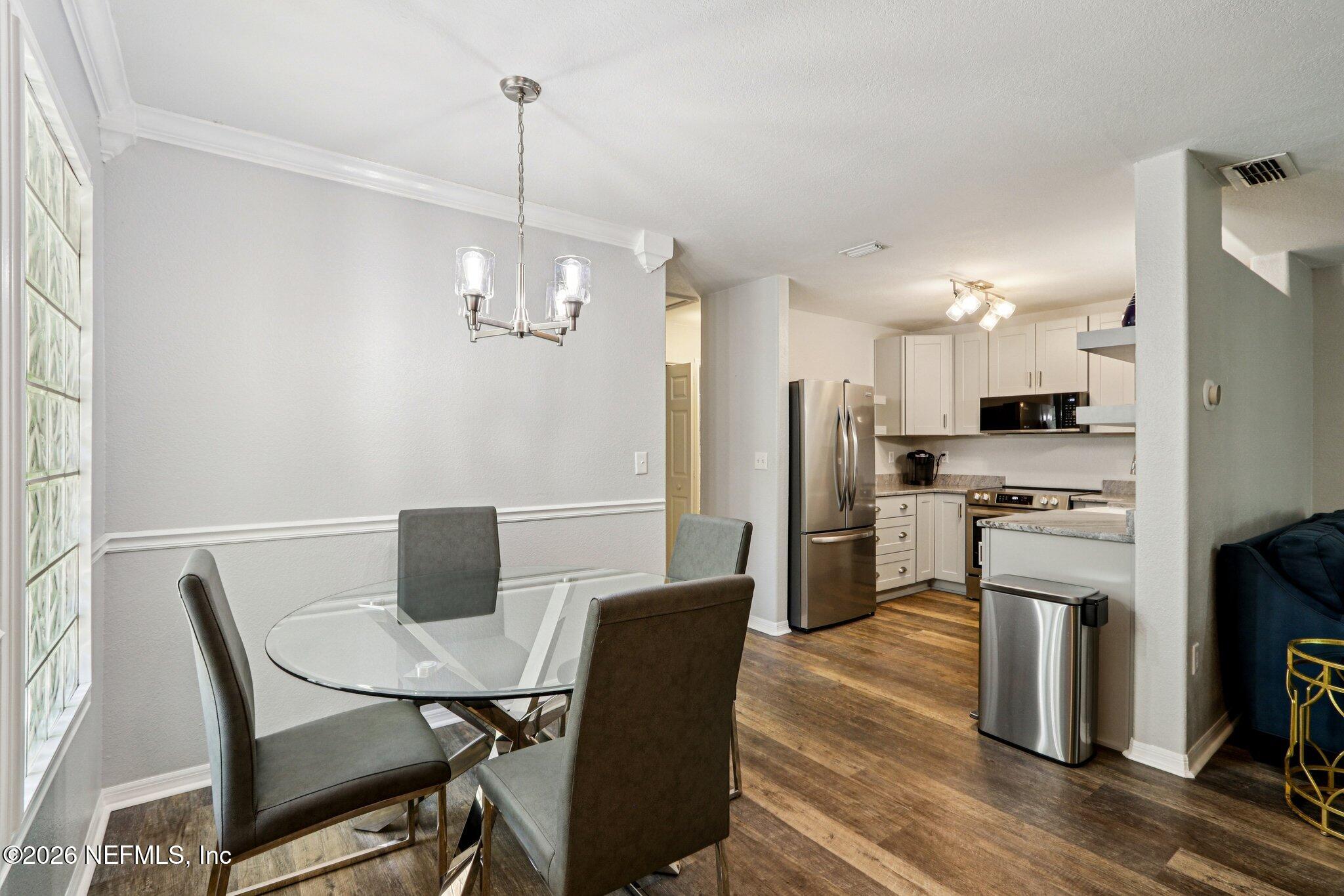 10150 Belle Rive Boulevard, Unit 102 Jacksonville, FL 32256 - Photo 6 of 33 a view of a dining room with furniture wooden floor and a chandelier