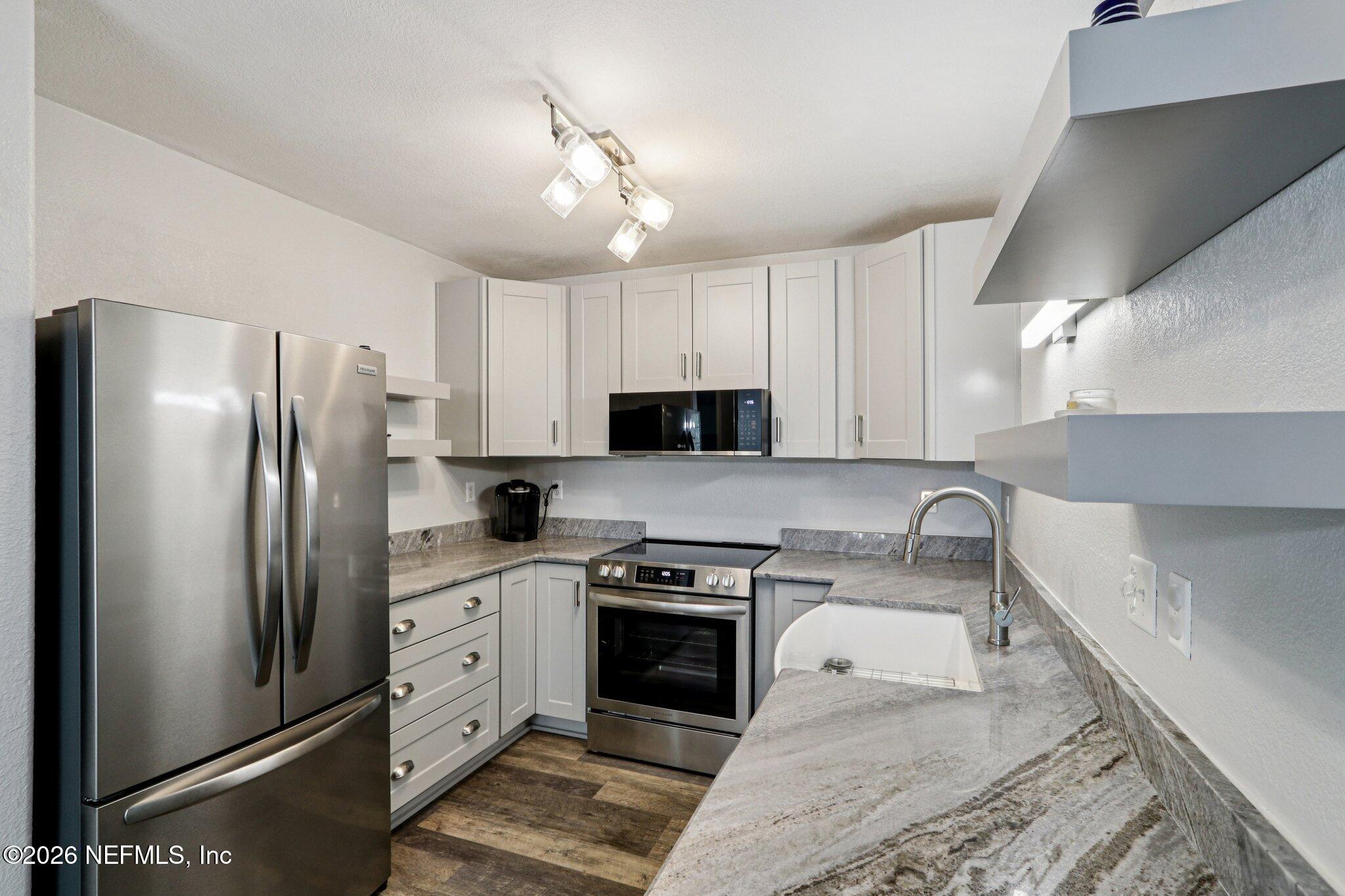 10150 Belle Rive Boulevard, Unit 102 Jacksonville, FL 32256 - Photo 8 of 33 a kitchen with stainless steel appliances granite countertop a refrigerator a stove a sink and white cabinets with wooden floor