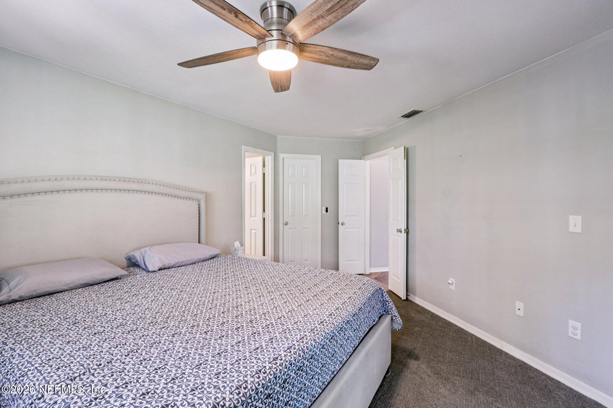 10150 Belle Rive Boulevard, Unit 102 Jacksonville, FL 32256 - Photo 10 of 33 a bedroom with a large bed and a chandelier fan