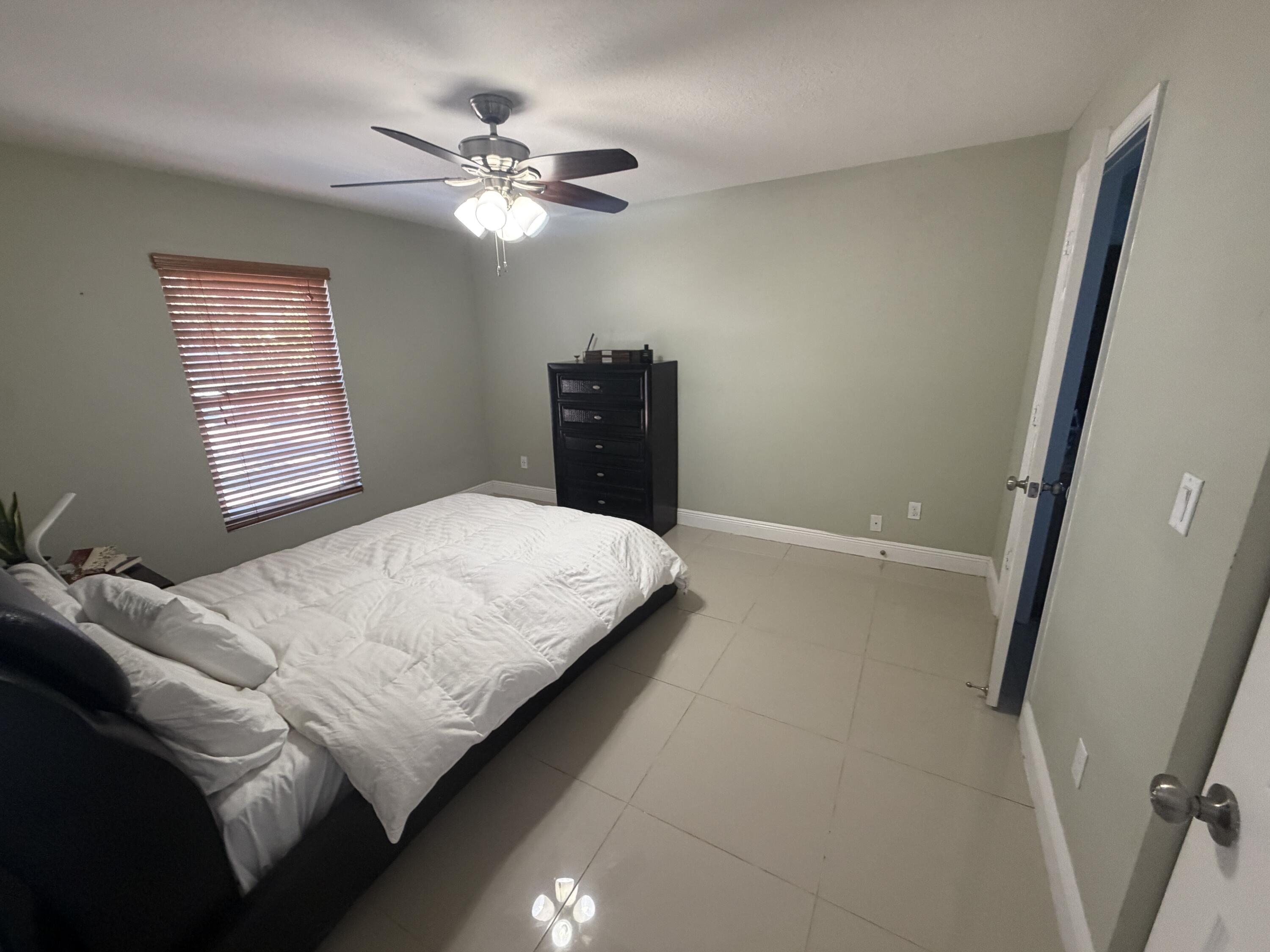 5928 Papaya Road Royal Palm Estates, FL 33413 - Photo 5 of 12 a bedroom with a bed and a chandelier