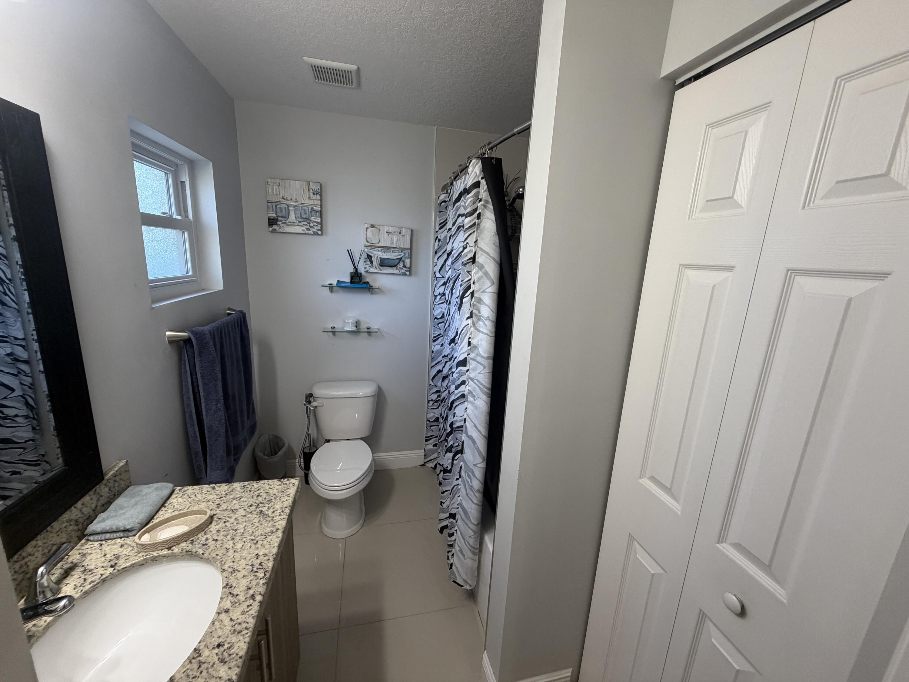 5928 Papaya Road Royal Palm Estates, FL 33413 - Photo 6 of 12 a bathroom with a granite countertop sink toilet and shower curtain