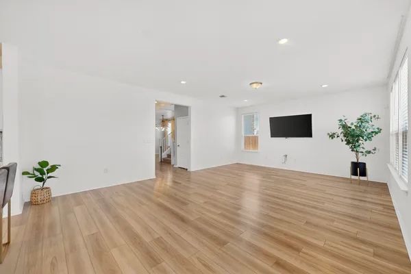 a view of an empty room with wooden floor and a potted plant