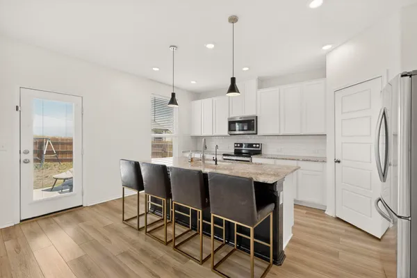 a kitchen with stainless steel appliances kitchen island a wooden floor and white cabinets