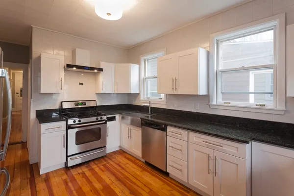 a kitchen with granite countertop wooden cabinets stainless steel appliances and a window