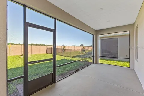 a view of an empty room with floor to ceiling windows with yard