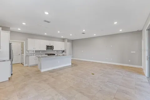 a large kitchen with kitchen island a sink a refrigerator and white cabinets