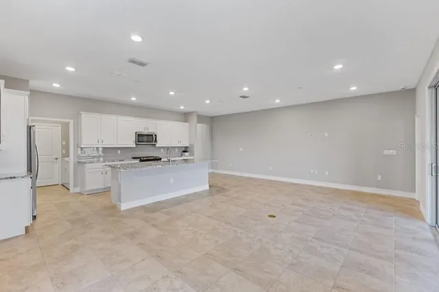 a large kitchen with kitchen island a sink a refrigerator and white cabinets