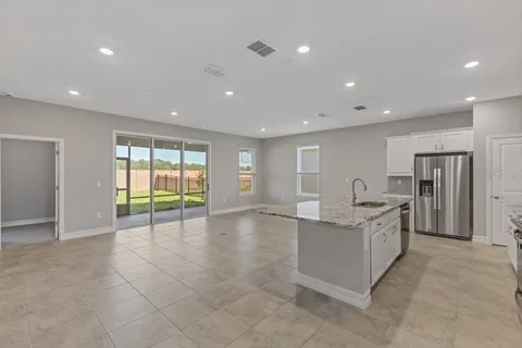 a view of an empty room with a window and kitchen view