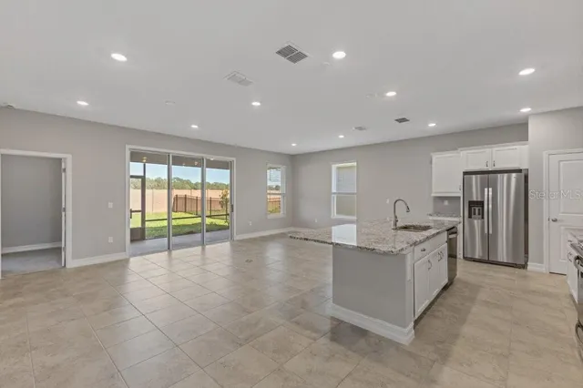 a view of an empty room with a window and kitchen view