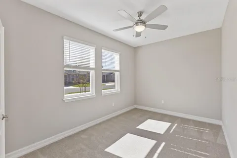 an empty room with windows and ceiling fan
