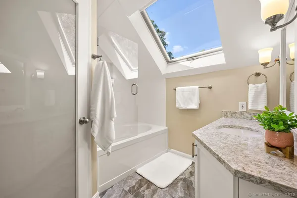 a bath room with a granite countertop sink a toilet and a mirror