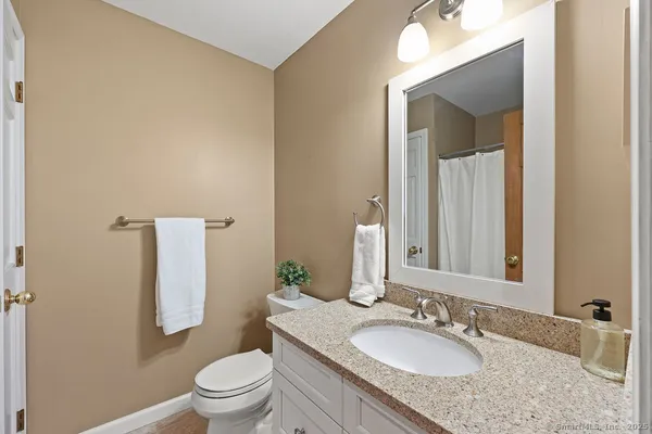 a bathroom with a granite countertop sink toilet and mirror