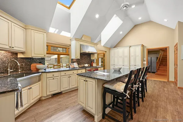 a kitchen with stainless steel appliances granite countertop a stove top oven a sink dishwasher a dining table and chairs with wooden floor