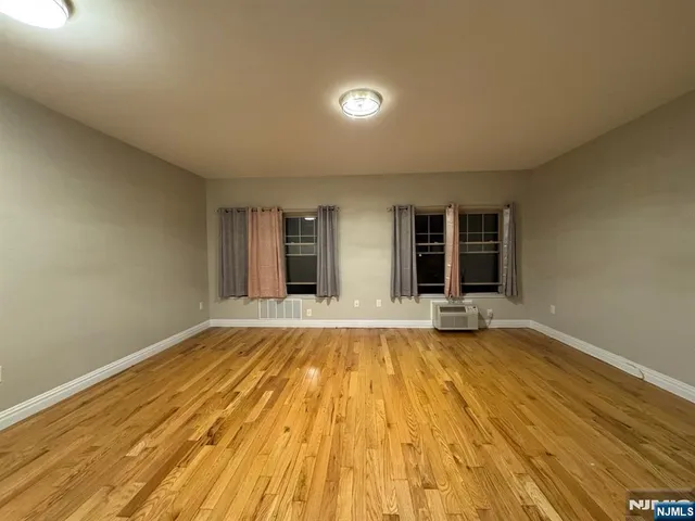 a view of an empty room with window and wooden floor