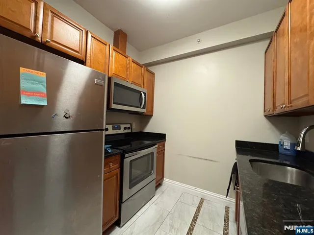 a kitchen with stainless steel appliances granite countertop a refrigerator a stove and a sink