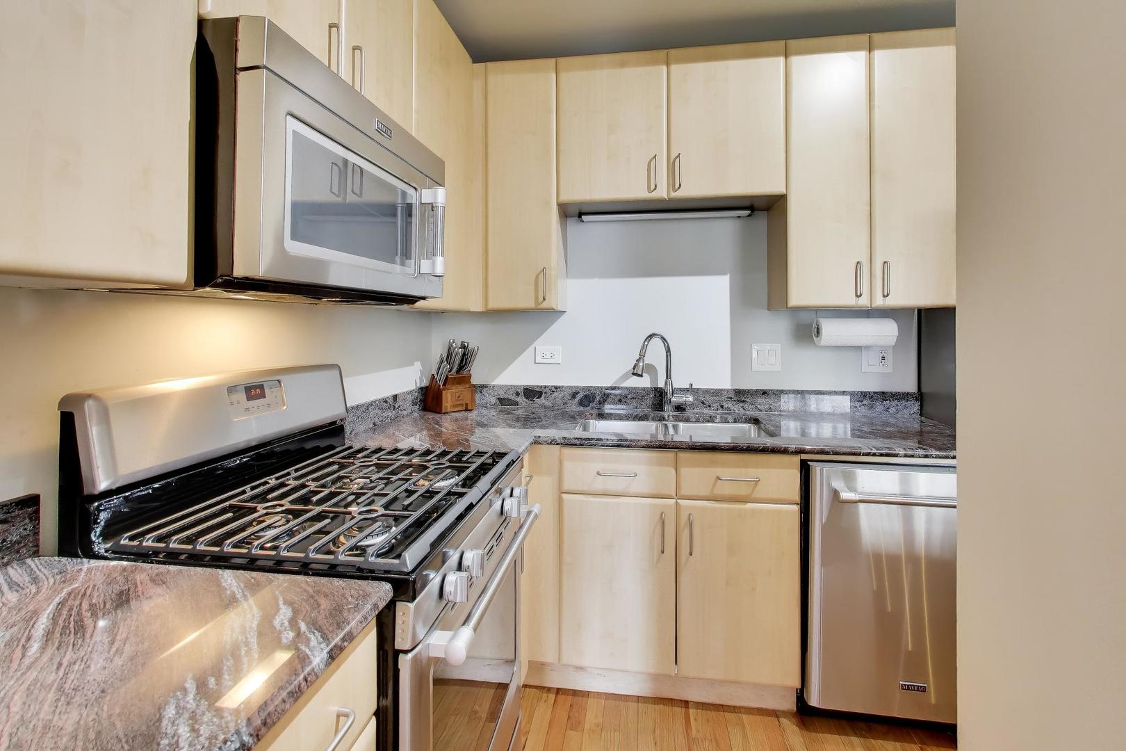 212 West Washington Street, Unit 908 Chicago, IL 60606 - Photo 11 of 32 a kitchen with granite countertop a stove sink and cabinets
