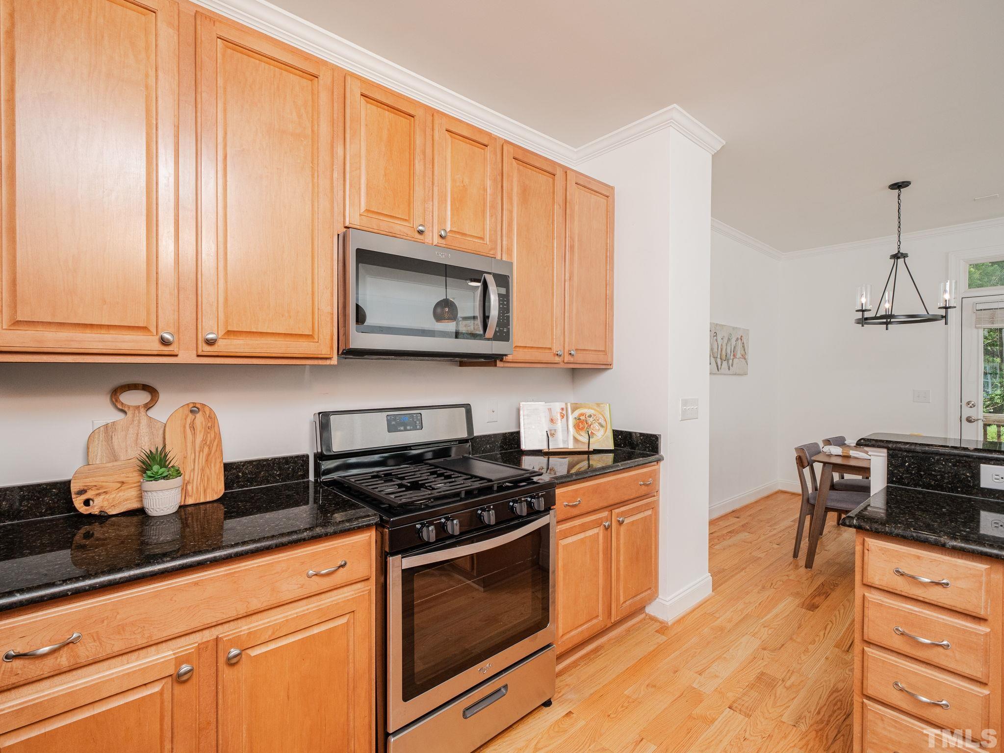 6109 Shandwick Court Raleigh, NC 27609 - Photo 13 of 36 a kitchen with stainless steel appliances granite countertop a stove a sink and a microwave