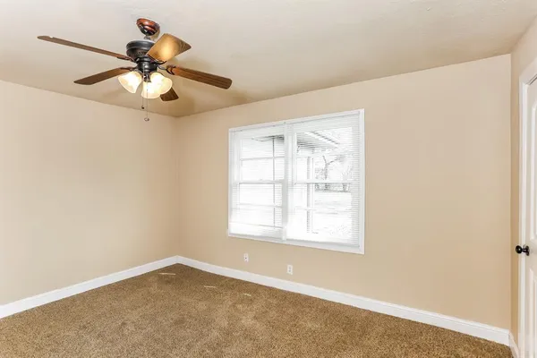 an empty room with a window and a fan