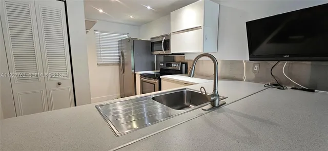a kitchen with stainless steel appliances a stove microwave and sink