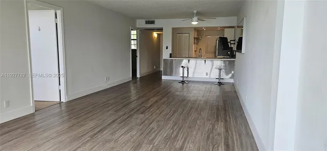 a view of a hallway with wooden floor and a kitchen