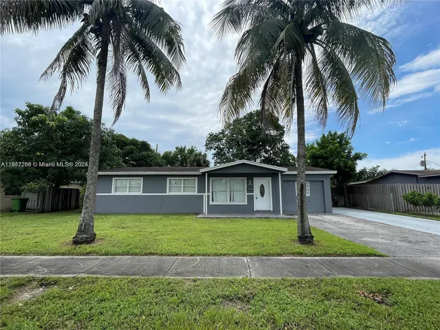 a front view of house with yard and palm tree