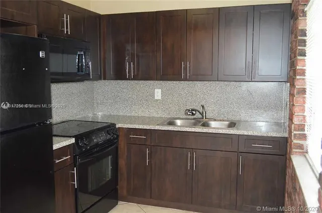 a kitchen with granite countertop a sink cabinets and stainless steel appliances
