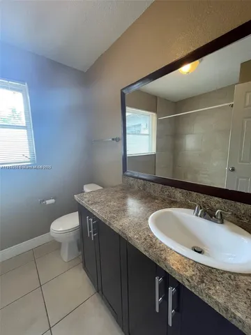 a bathroom with a granite countertop sink a toilet and a mirror