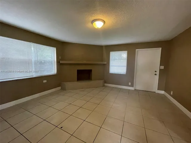 a view of an empty room with a fireplace and a window