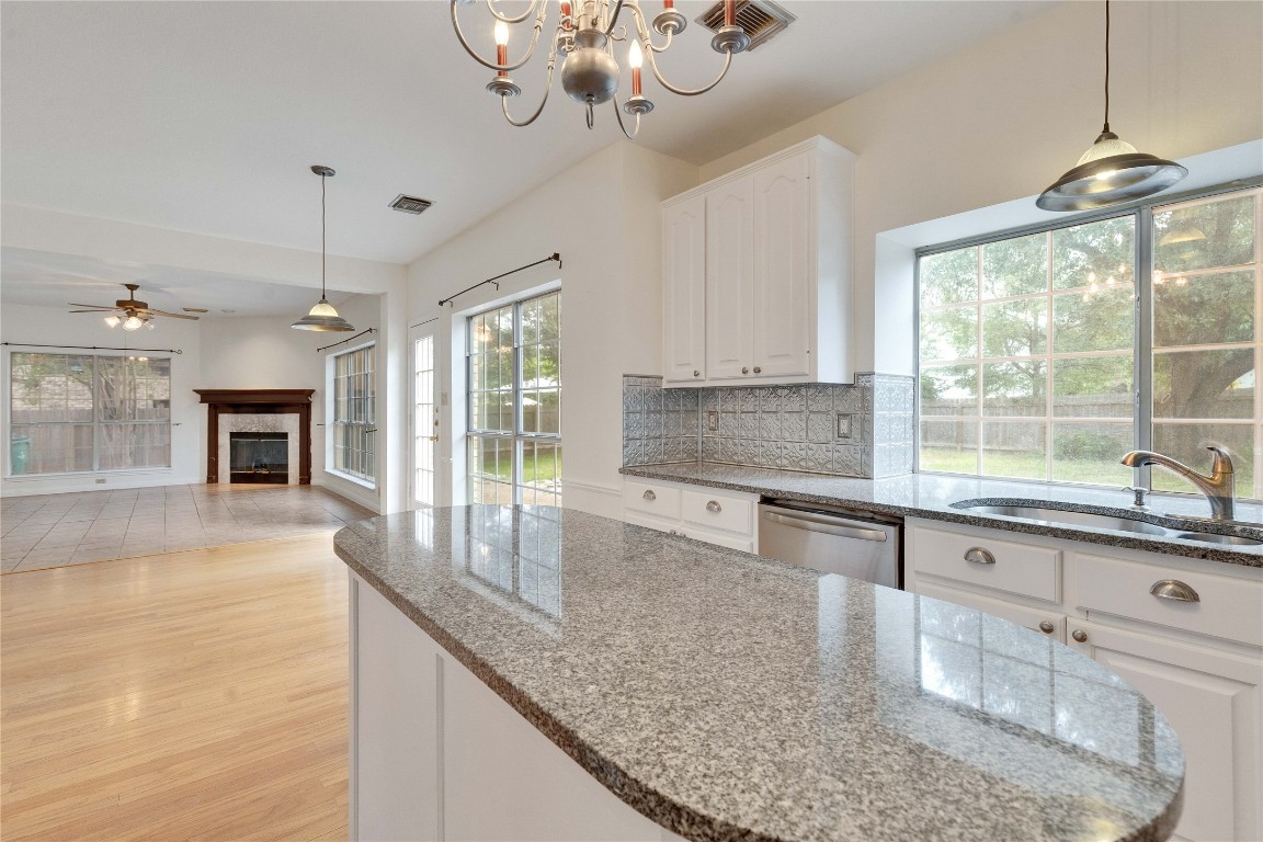 5407 Merrywing Circle Austin, TX 78730 - Photo 14 of 36 Kitchen featuring pendant lighting, white cabinets, dark stone counters, a tile fireplace, and backsplash
