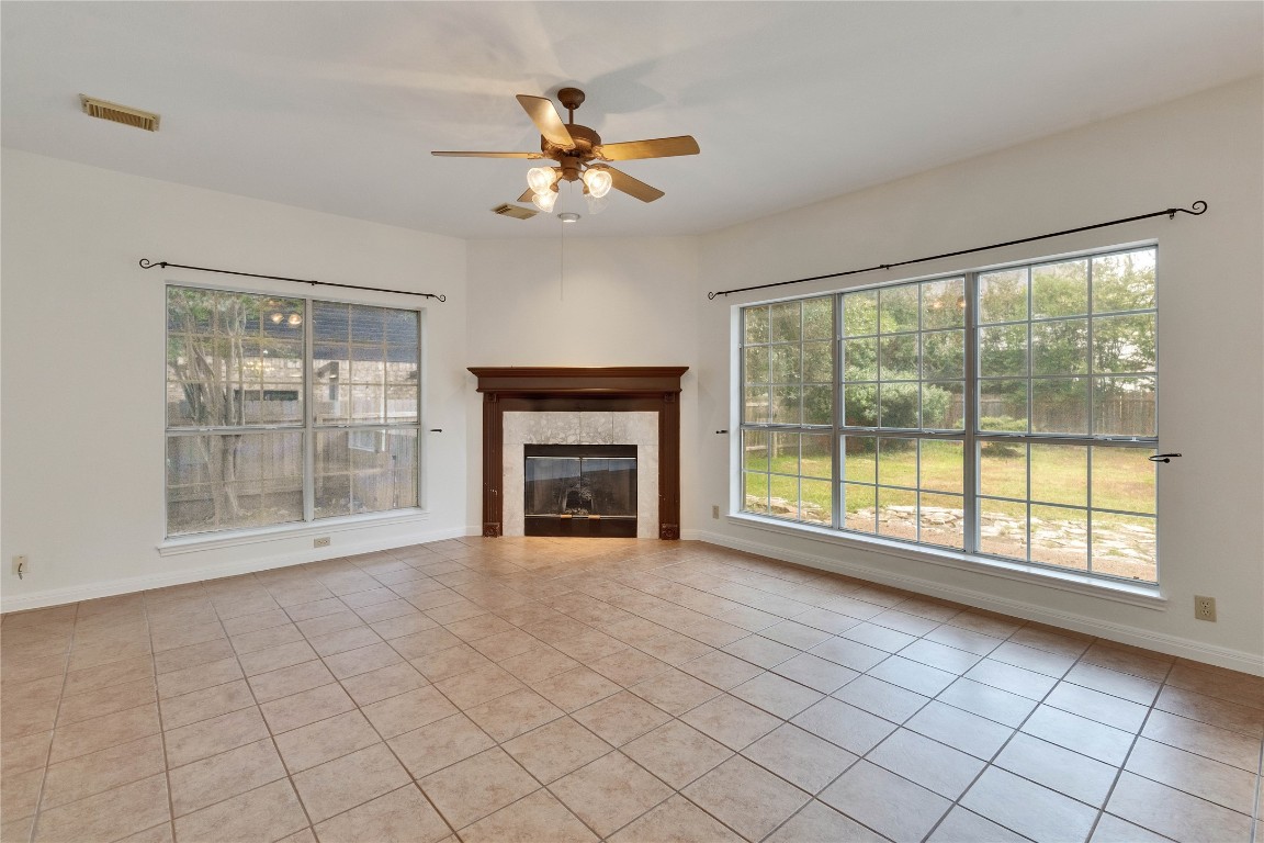 5407 Merrywing Circle Austin, TX 78730 - Photo 15 of 36 Unfurnished living room featuring light tile patterned floors, healthy amount of natural light, and a tiled fireplace