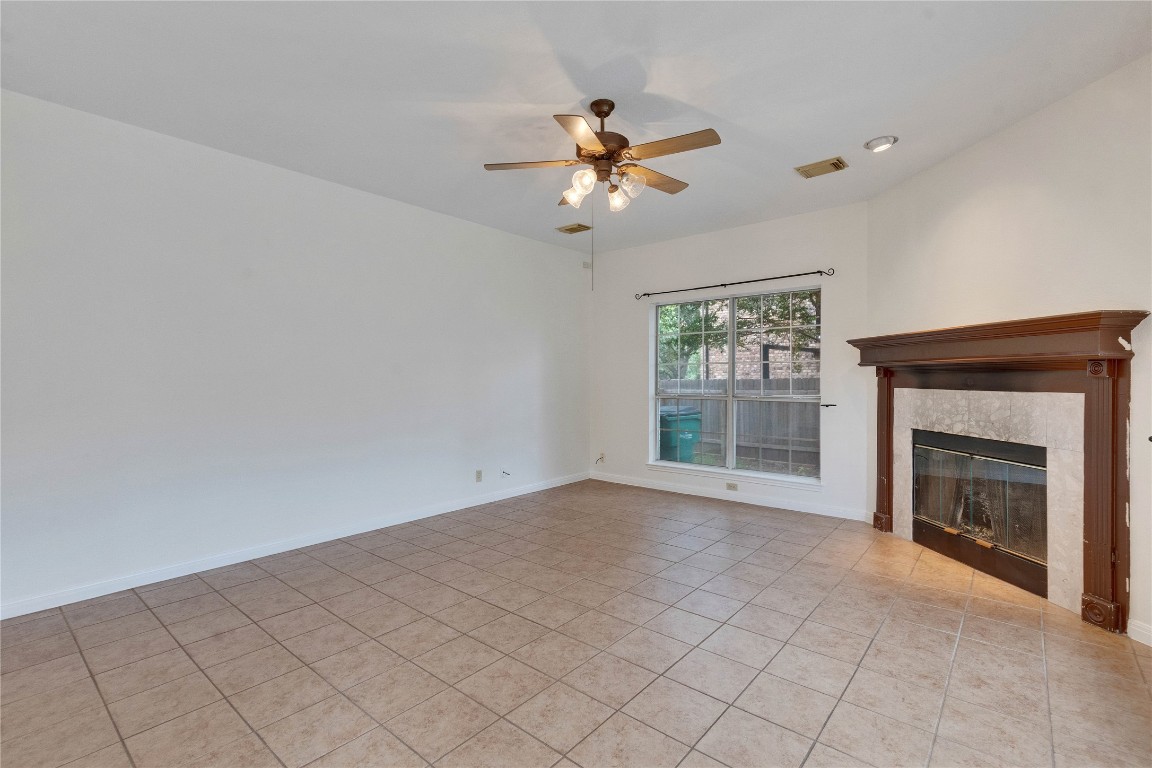 5407 Merrywing Circle Austin, TX 78730 - Photo 16 of 36 Unfurnished living room featuring light tile patterned flooring, a tiled fireplace, and a ceiling fan