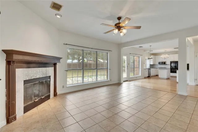 a view of an empty room with a fireplace and a chandelier fan