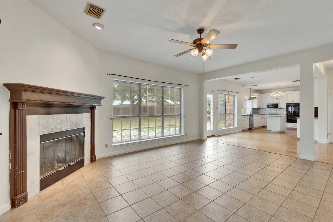 5407 Merrywing Circle Austin, TX 78730 - Photo 17 of 36 Unfurnished living room featuring light tile patterned floors, a tile fireplace, a chandelier, ceiling fan, and recessed lighting