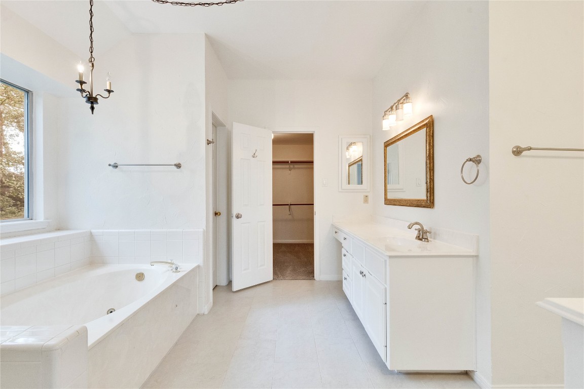 5407 Merrywing Circle Austin, TX 78730 - Photo 30 of 36 Bathroom with a walk in closet, vanity, a bath, and light tile patterned floors