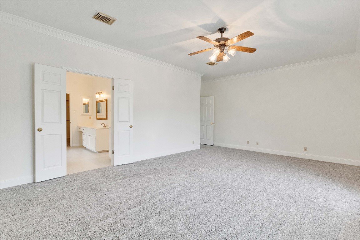 5407 Merrywing Circle Austin, TX 78730 - Photo 33 of 36 Unfurnished bedroom with light colored carpet, ornamental molding, a ceiling fan, and ensuite bath