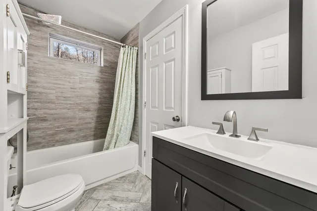 a bathroom with a sink a toilet a mirror a bathtub and shower