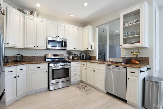 a kitchen with granite countertop white cabinets white stainless steel appliances with a sink and dishwasher