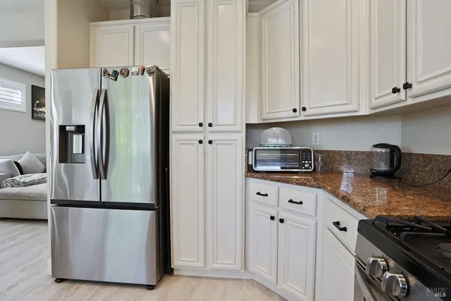 a kitchen with stainless steel appliances granite countertop a refrigerator a stove and white cabinets