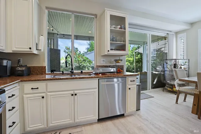 a kitchen with white cabinets and window