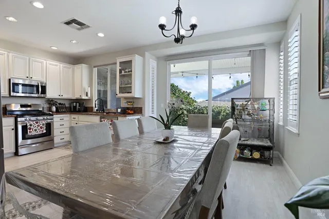 a kitchen with stainless steel appliances granite countertop a stove top oven a sink a dining table and chairs with wooden floor