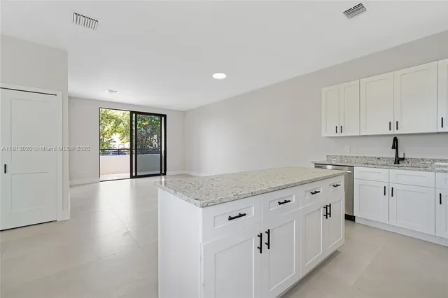 a kitchen with granite countertop a sink and dishwasher with white cabinets