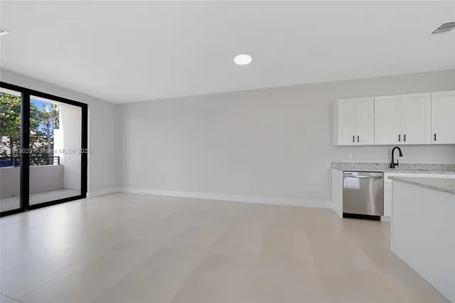 a view of an empty room with a kitchen and a window