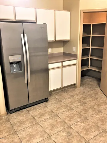 a view of a refrigerator in kitchen and an empty room