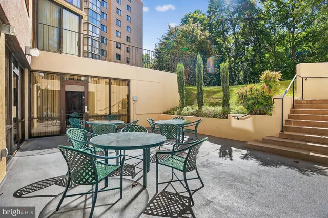 a patio with table and chairs and potted plants