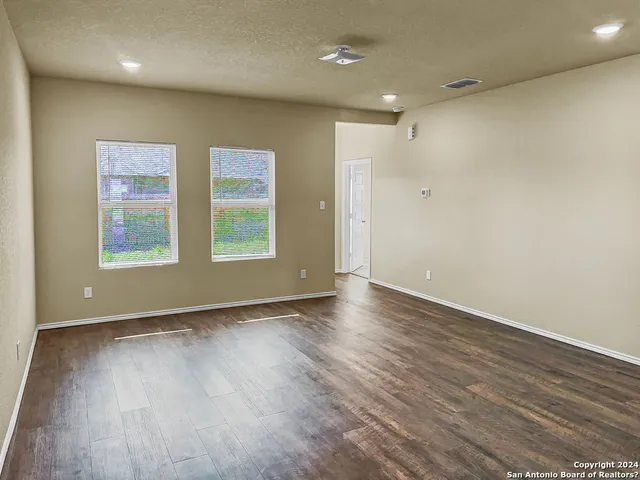an empty room with wooden floor and windows