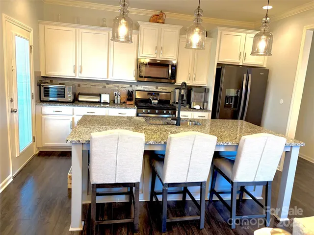 a kitchen with stainless steel appliances a dining table chairs and granite counter tops