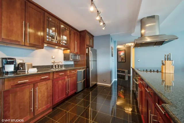 a kitchen with stainless steel appliances granite countertop a refrigerator a sink and wooden cabinets
