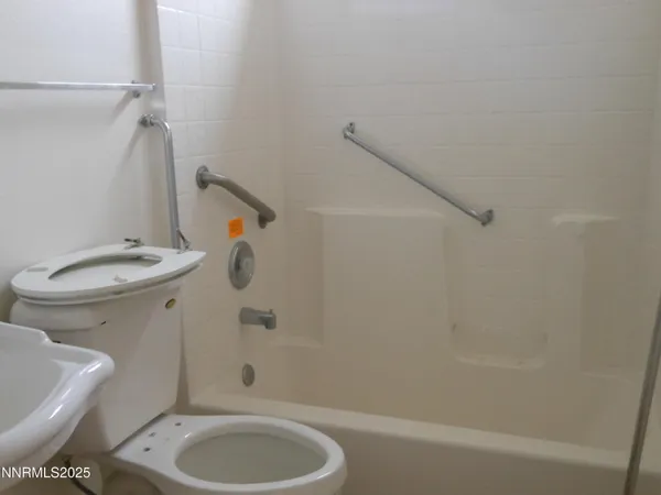a bathroom with a granite countertop toilet and a bathtub