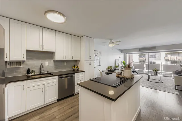 a kitchen with a stove a sink a refrigerator and white cabinets with wooden floor